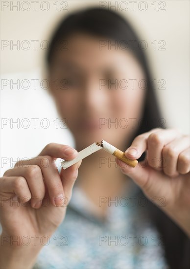 Mixed race teenage girl breaking cigarette in half