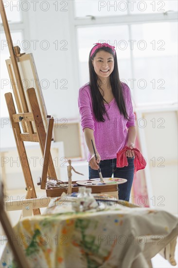 Mixed race teenage girl painting in studio