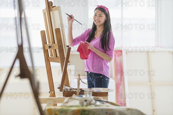 Mixed race teenage girl painting in studio