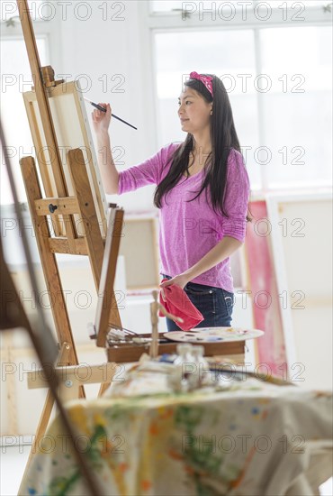 Mixed race teenage girl painting in studio