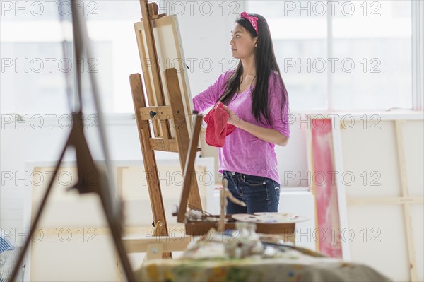 Mixed race teenage girl painting in studio