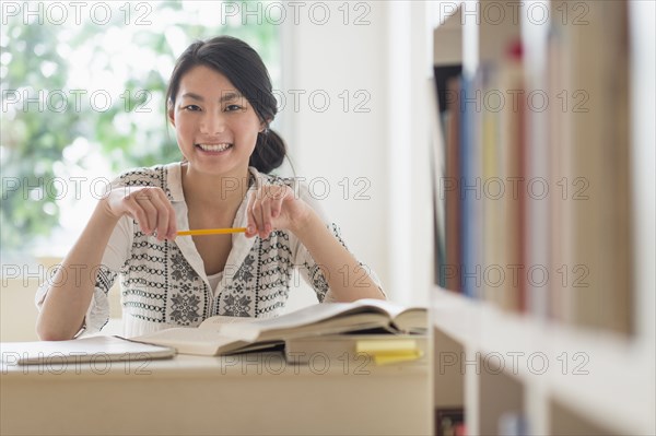 Mixed race teenage girl studying in library