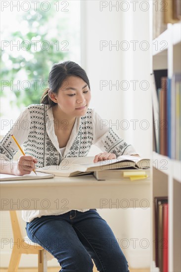 Mixed race teenage girl studying in library