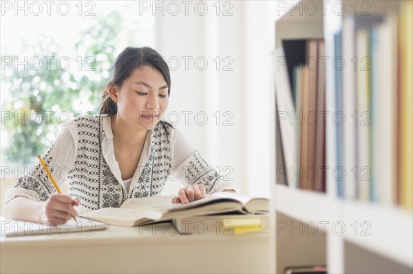 Mixed race teenage girl studying in library