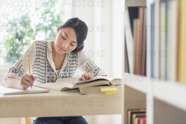 Mixed race teenage girl studying in library