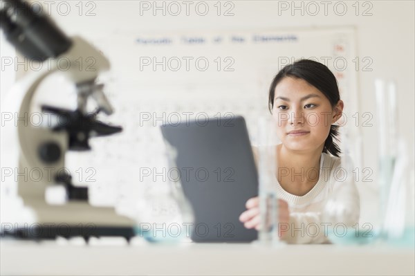 Mixed race teenage girl using laptop computer in science lab