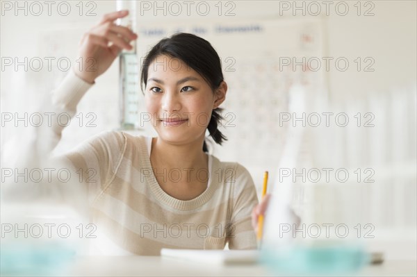 Mixed race teenage girl doing experiment in science lab