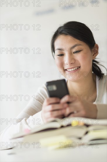 Mixed race teenage girl using cell phone in class