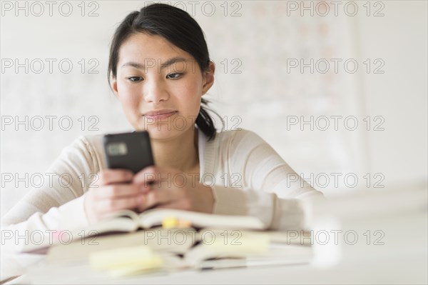 Mixed race teenage girl using cell phone in class