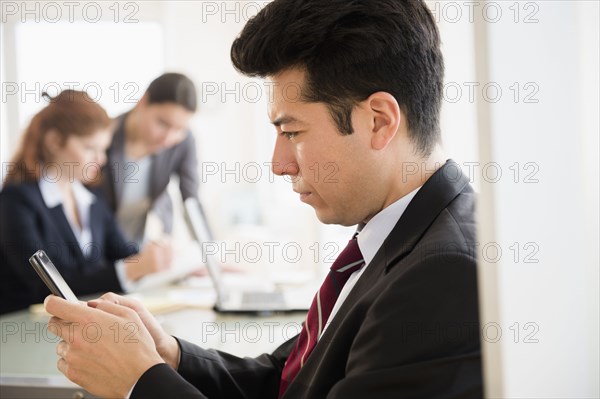 Businessman using cell phone in office