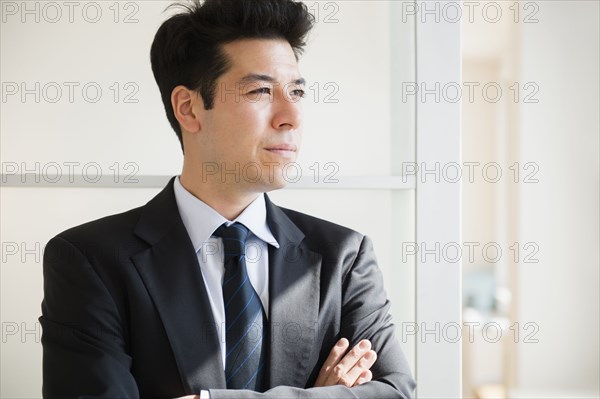 Mixed race businessman standing at window