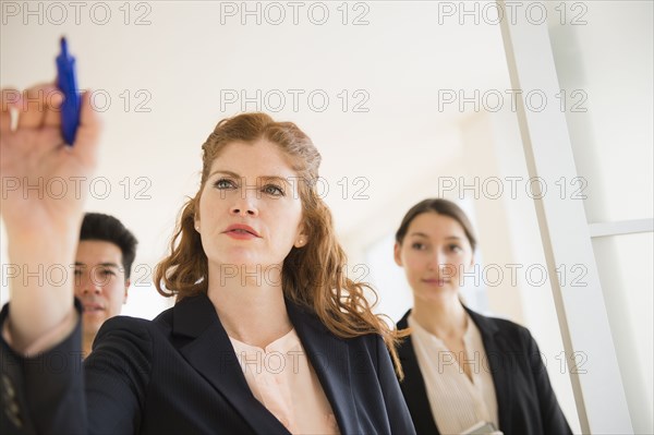 Businesswoman writing on window in office