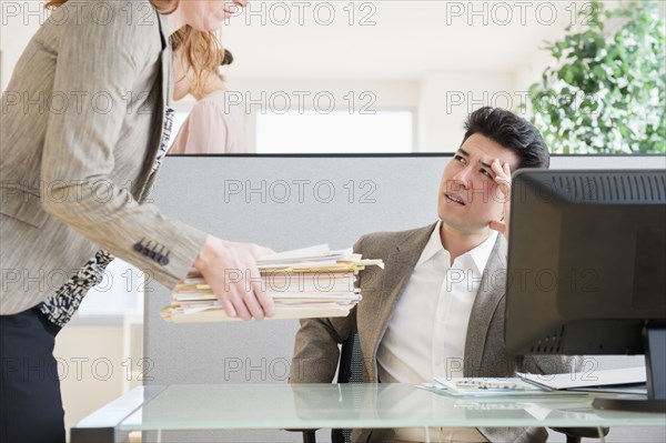 Businesswoman giving colleague stack of papers
