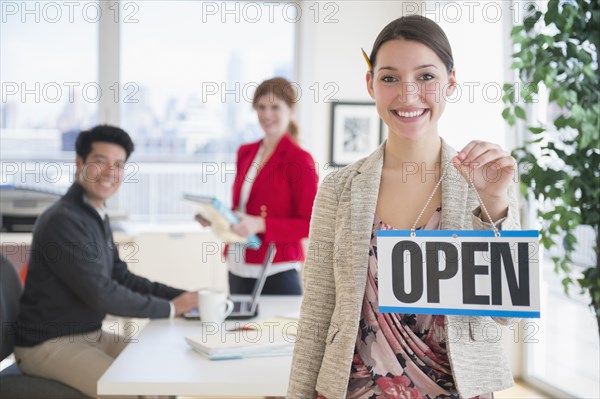 Businesswoman holding Open sign in office