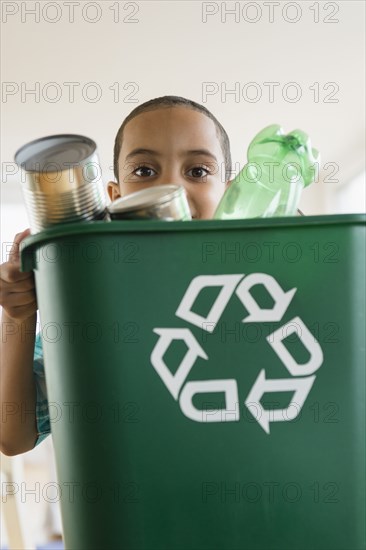 Mixed race boy carrying recycling