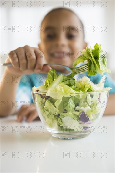 Mixed race boy eating salad