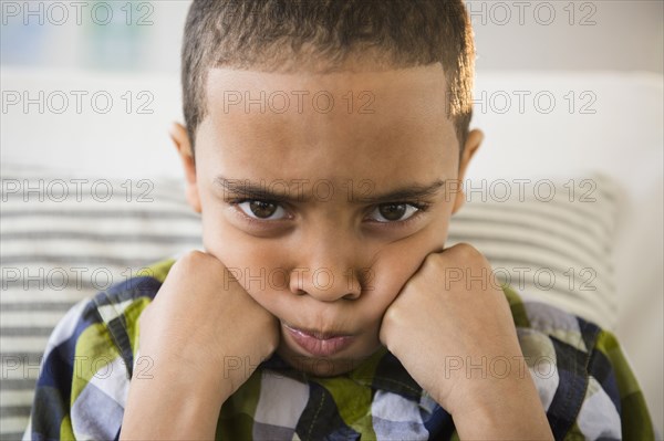 Mixed race boy pouting on sofa