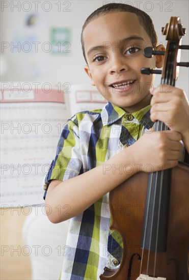 Mixed race boy holding violin