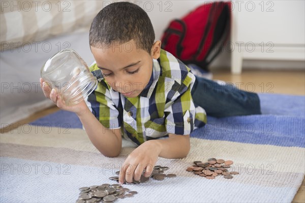 Mixed race boy counting change on floor