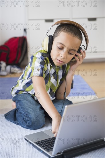 Mixed race boy listening to headphones on laptop