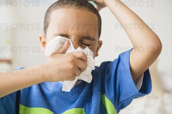 Mixed race boy blowing his nose