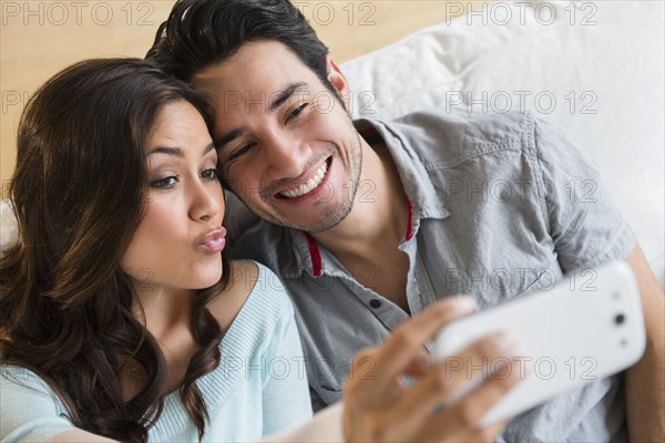 Couple taking pictures together on sofa