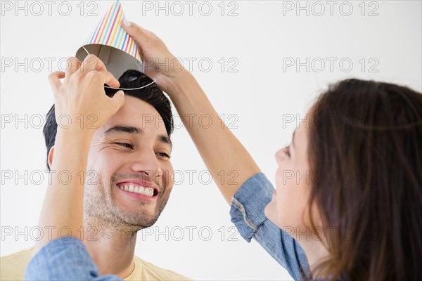 Woman putting party hat on boyfriend