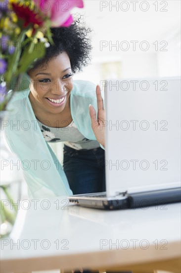 African American woman video chatting with laptop