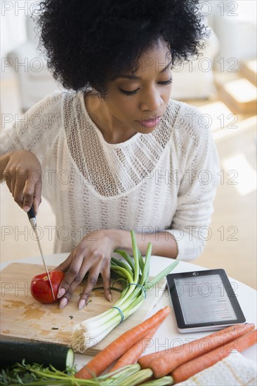 African American woman using tablet computer to cook