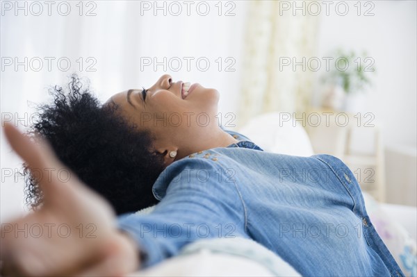 African American woman with arms outstretched on sofa