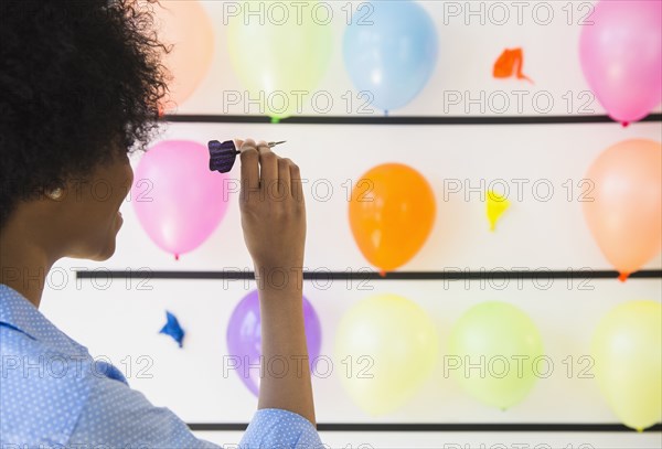 African American woman popping balloons with dart