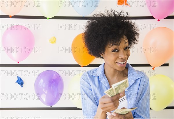 African American woman counting money at balloon wall