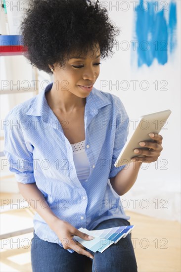 African American woman using tablet computer to select paint color