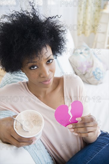 African American woman holding broken heart and ice cream
