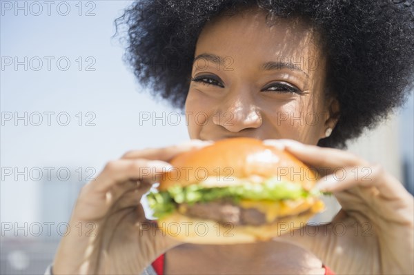 African American woman eating cheeseburger