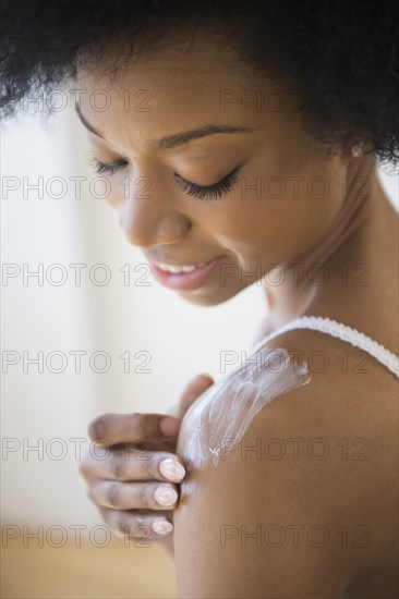 African American woman applying moisturizer