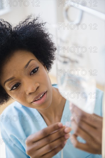 African American nurse connecting intravenous bag