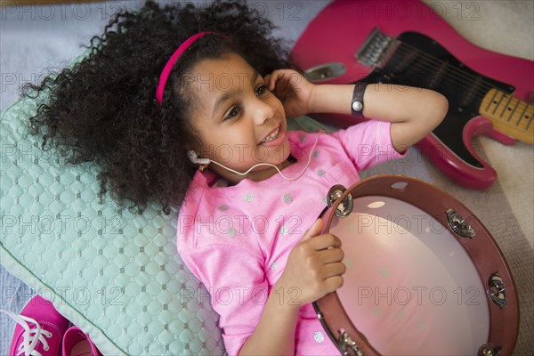 African American girl listening to music holding tambourine