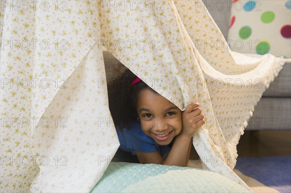 African American girl playing in blanket fort