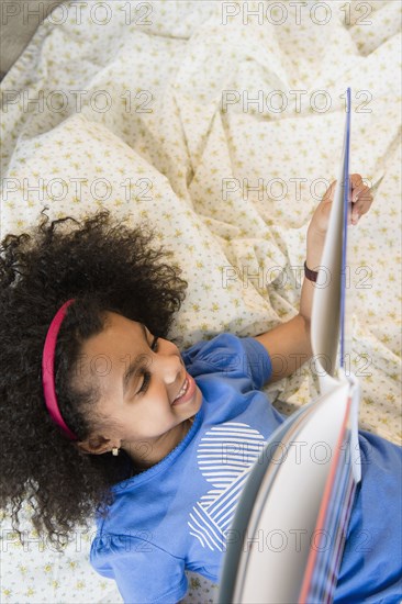 African American girl reading on blanket