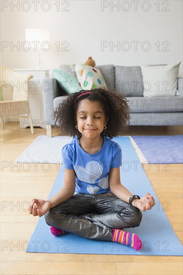 African American girl meditating on yoga mat