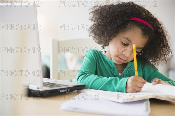 African American girl doing homework with laptop