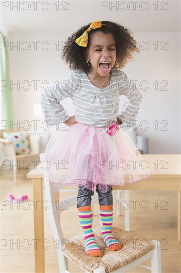 African American girl shouting on chair