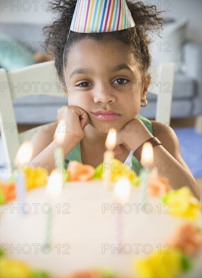 African American girl pouting at birthday cake