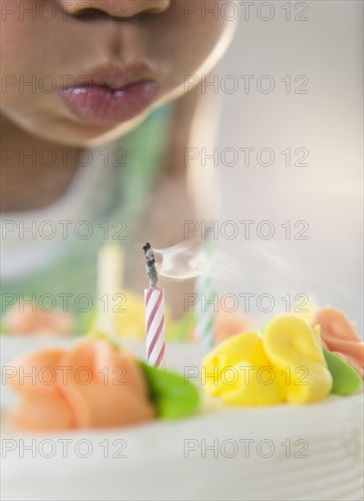 African American girl blowing out candles on birthday cake