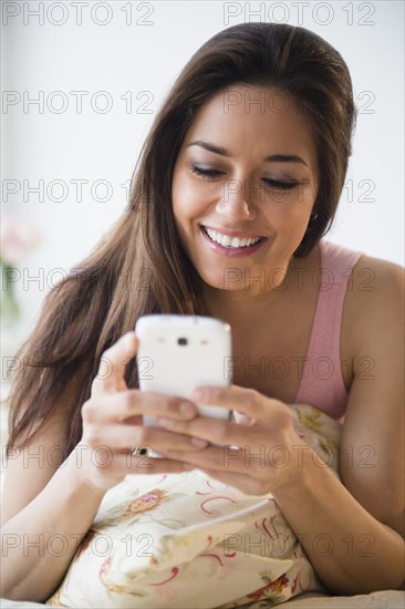 Woman using cell phone on bed