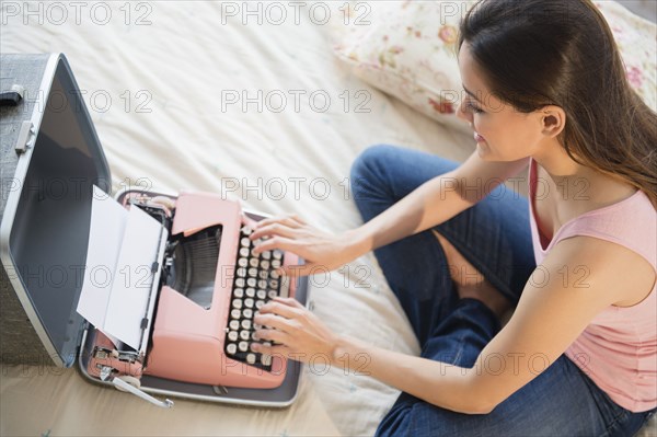 Woman using typewriter on bed