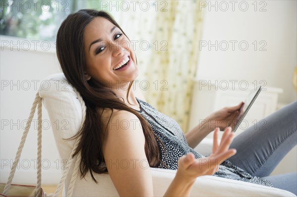 Woman using tablet computer in armchair