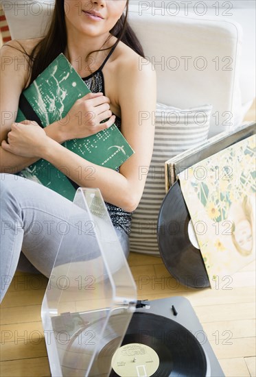 Woman holding vinyl records in living room