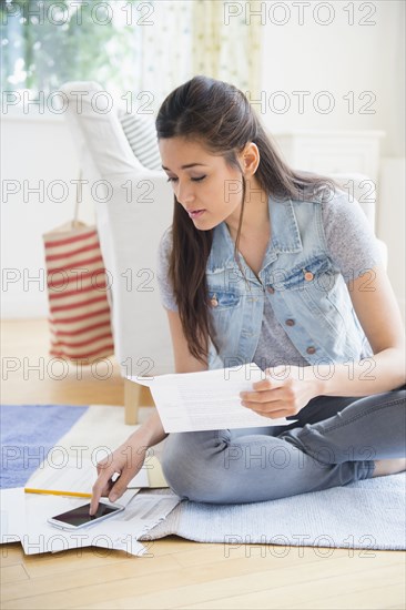 Woman using cell phone and taking notes